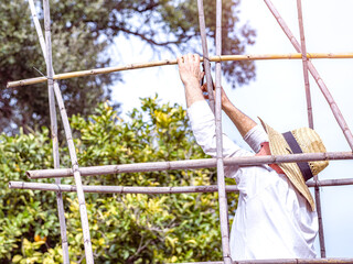 Farmer building a structure on the farm to grow tomatoes. Selective focus.