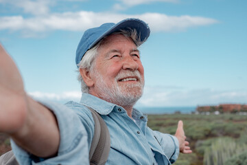 Portrait of happy senior bearded man outdoors in trekking day looking away. Elderly grandfather smiling enjoying healthy lifestyle and nature.