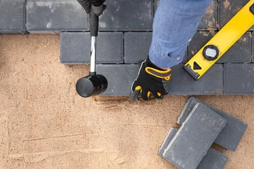 Foto op Plexiglas Laying cement pavement on a walkway with a rubber hammer and gloves on a sand. House improvement. © artursfoto