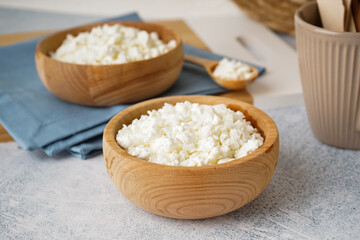 Bowl with tasty cottage cheese on light grunge background