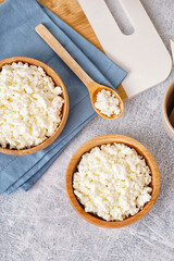 Bowls with tasty cottage cheese on light grunge background