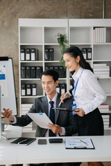 Asian business colleague business presents and explains and using laptop and tablet. Teamwork, financial marketing team, while sitting in office room.