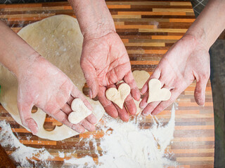 hands of grandmother, mother and granddaughter holding heart-shaped dough, three generations concept, heart-shaped cookies, family hearth, close-up, baking with love, anniversary, family hearth,