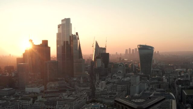 Aerial slider shot City of London skyscrapers at dawn to the Thames revealing Canary Wharf.