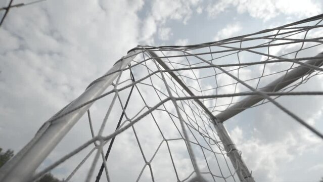 Low angle shot of the net of a football goal in slowmotion on a cloudy day LOG