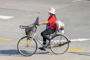 Foto auf Acrylglas A lottery saleswoman rides a bicycle, Thailand © milkovasa