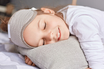 Fototapeta na wymiar Adorable Caucasian girl sleeping well in cozy bed, cute little kid lying on soft pillow napping, calm child resting, healthy peaceful sleep in bedroom.