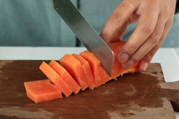 Cutting or Slicing Peeled Ripe Papaya on Wooden Chopping Board