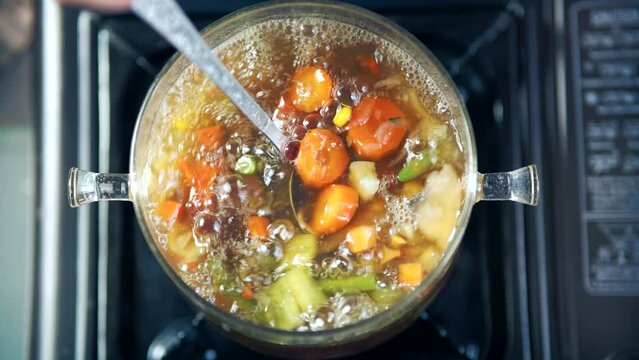 stirring of vegetable soup in pot with ladle	