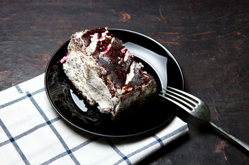 Plate with slice of tasty chocolate cake on table. Yummy dessert on on wooden background, closeup
