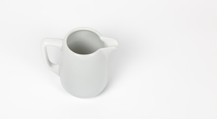 Milk jug on white background. Porcelain sauce boat, pitcher, creamer or ceramic gravy boat. Space for text, for advertising, banner, signboard, menu and printed materials