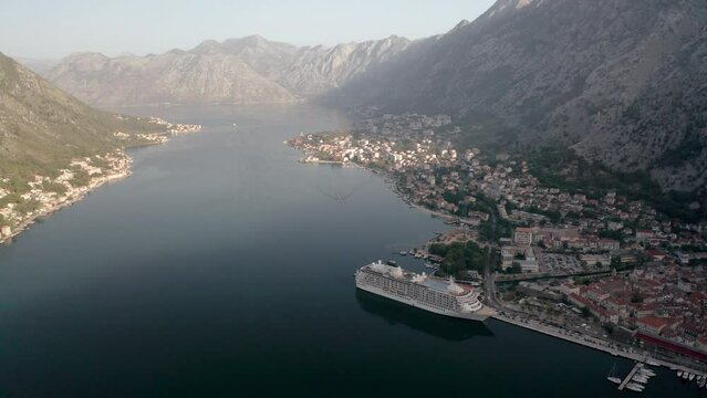 Aerial panoramic video of the picturesque bay of Kotor (Boka Kotor) with beautiful coastline, red roofs, marina with boats and big cruise ship, Montenegro.