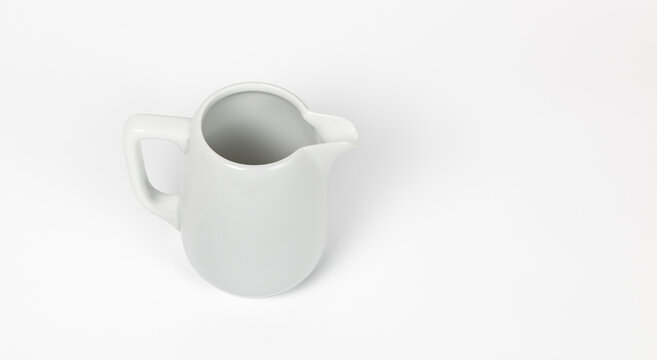 Milk jug on white background. Porcelain sauce boat, pitcher, creamer or ceramic gravy boat. Space for text, for advertising, banner, signboard, menu and printed materials