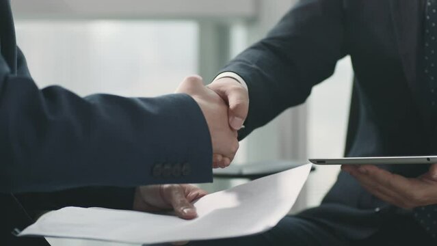 two asian business men reaching an agreement and shaking hands in office