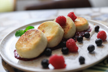 Cheesecakes served on plate with berries, cream and sugar powder ready for eating in restaurant