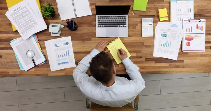 Businessman making to do list in notebook at table in office top view 4k movie. Business planning and organization concept