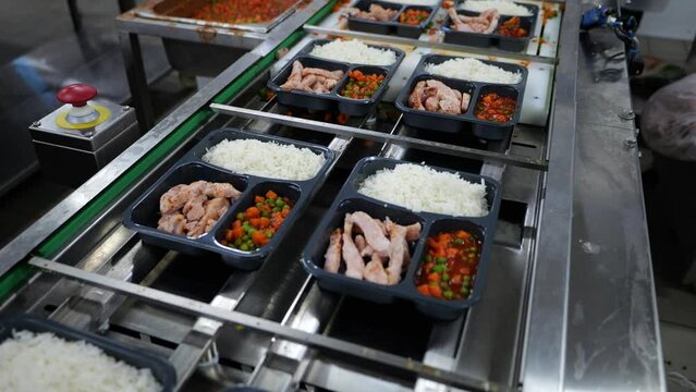 Food Factory catering. Close up of catering food portion packing by machine.