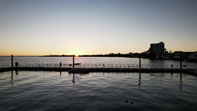 A picturesque landscape where one can enjoy a breathtaking view of the sunset over a tranquil body of water intersected by a pier.