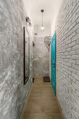 Turquoise door in the hallway, with a large mirror and brick walls