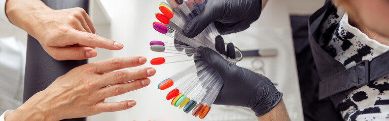 Manicure master helping to choose polish color in studio