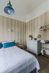 Bed in a small bedroom with turquoise pillows