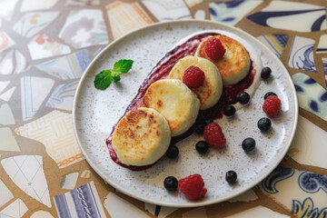 Cheesecakes served on plate with berries, cream and sugar powder ready for eating in restaurant