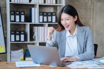 Asian business woman are excited business success with inspiration from their excellent financial results that are happy working in a modern office on a computer.