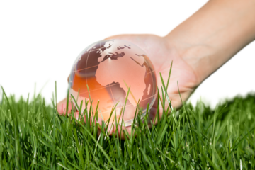 Glass world in hand on green grass