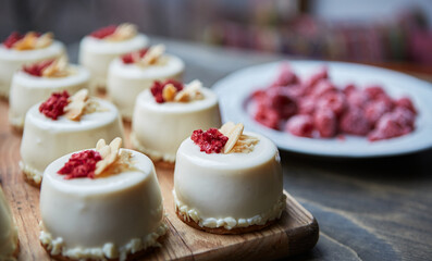 Delicious white cakes with dried raspberries baked in a pastry cafe and served on a wooden board