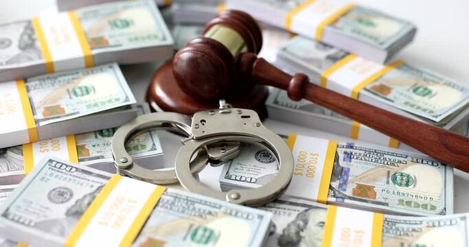 Judge gavel and handcuffs put among packs of dollar money cash on white table. Financial corruption and stealing crime sentence at court slow motion