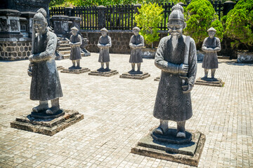 Fototapeta premium Ancient stone statues of warriors and pheasants in the courtyard of a temple at Hue in Vietnam