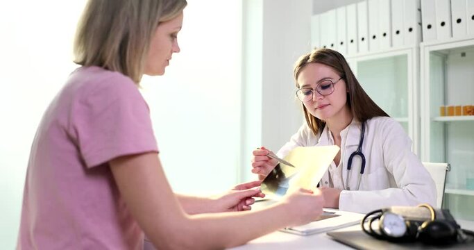 Woman medical specialist points to damaged area of lungs to female patient. Sick lady listens carefully to doctor prescribing treatment slow motion