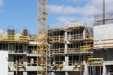 Construction site background. Block of flats in progress. Apartments building. Yellow crane and scaffolding. Real estate industry.