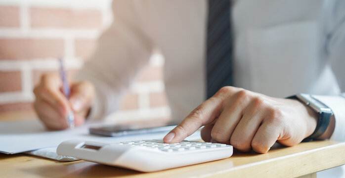 close up banker employee man press on calculator to check about profit or financial annual of company in room for business concept