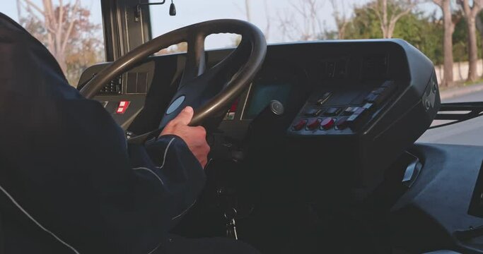 Close up of male hands. The driver is sitting at steering wheel of a bus
