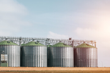 Obraz premium A large grain storage tank with a green roof sits in a field.
