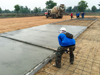 A worker adjusts levels of concrete in formwork using a trowel. For smoothing and polishing concrete slab.