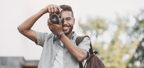 Young man photographer takes photographs with dslr camera in a city, banner. Travel, vacations,...