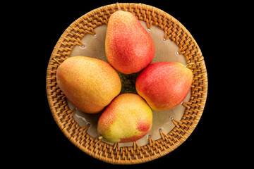 Four organic pears in ceramic plate isolated on black background, top view, macro.