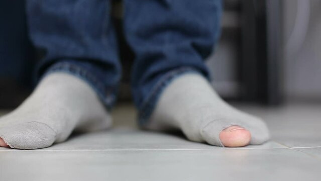 A man stands in torn socks.