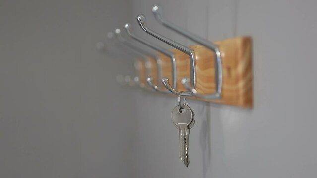 The man hangs and takes the keys to the apartment on the hanger. Looped video.
