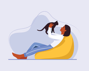 dark-skinned girl with short hair sits on a bean bag chair with a cat