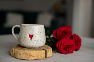 A cup of warm, warming aromatic tea, coffee, flowers nearby