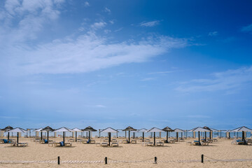 Beach with no one in the Algarve, in spring, with modern umbrellas but empty of tourists