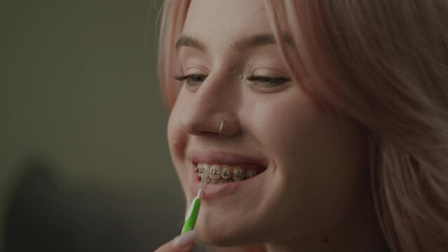 Woman Cleaning Dental Braces With Brush. Female brushing her teeth with braces with special brush. Close Up.