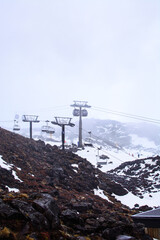 Cable cars and ski lifts going up and down snow blanketed slopes of the mountain while a snow storm building up. Mt Ruapehu, Whakapapa Ski Field, New Zealand