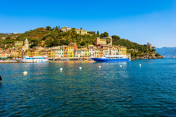 Fototapeta premium Tourist ferries in the famous village of Portofino, luxury tourist resort in Genoa Province, Liguria, Italy, Europe. Port and colorful houses, Mediterranean sea (Ligurian sea).