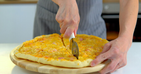 Woman cutting fresh baked homemade pizza, close up