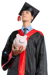Happy young graduation man with piggy bank