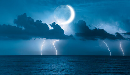 Night sky with lightning on crescent moon in the clouds on the fore ground calm blue sea 